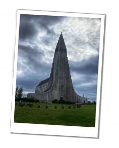 An imposing church spire juts into a dusky grey sky